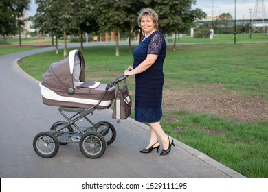 Grandmother with a baby boy in a stroller in a city park