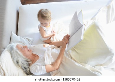Grand-mère et bébé fille se reposant au lit : photo de stock