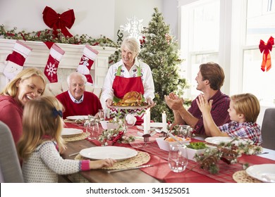 Grandmother Bringing Out Turkey At Family Christmas Meal