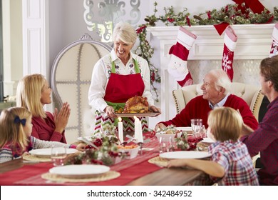 Grandmother Bringing Out Turkey At Family Christmas Meal