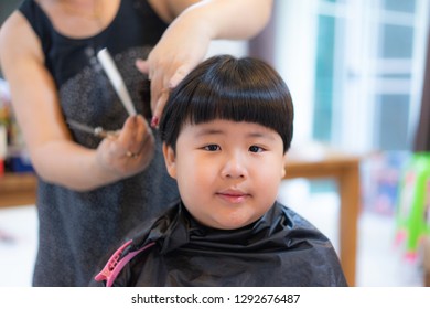 Grandmother is cutting hair of her fat grandson at home.