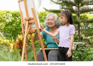 Grandmother drawing picture with kid girl in garden, Senior woman and her granddaughter play together in the garden - Powered by Shutterstock