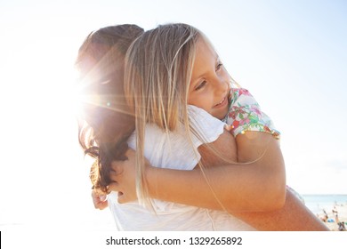 Grandmother And Grand Daughter Enjoy Sunny Beach Holiday Together, Joyful Smiling With Sun Flare Sky, Outdoors Space. Senior And Child Loving Fun Bonding Family Travel Activities, Leisure Lifestyle.