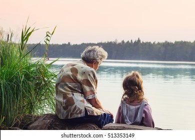 Grandmother with grandchild - senior woman and child looking at the river in warm summer day