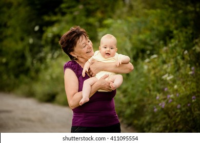 Grandmother With Grandchild - Senior Woman Holding Her Granddaughter Outdoor In Nature