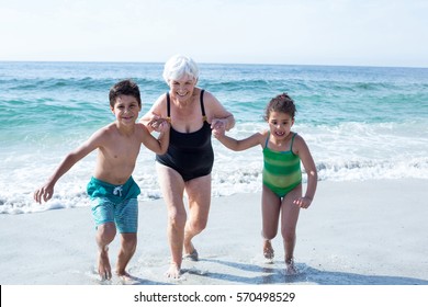 Grandmother with grandchildren running on sea shore at beach - Powered by Shutterstock