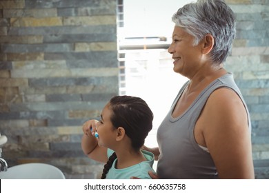 Grandmother and granddaughter brushing teeth in the bathroom at home