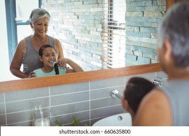 Grandmother and granddaughter brushing teeth in the bathroom at home