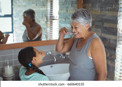 Grandmother and granddaughter brushing teeth in the bathroom at home
