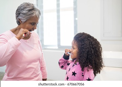 Grandmother and granddaughter brushing teeth in the bathroom at home