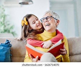 Grandmother and granddaughter having fun together and reading a book at home - Powered by Shutterstock