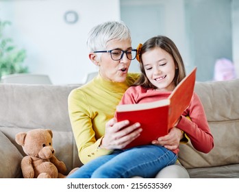 Grandmother and granddaughter having fun together and reading a book at home - Powered by Shutterstock