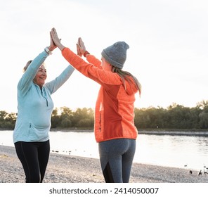 Grandmother and granddaughter high-fiving after training at the river - Powered by Shutterstock