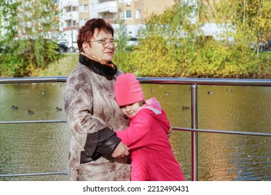 Grandmother And Granddaughter Hugging. Having Good Times With Grandparent In Autumn Park