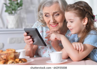 Grandmother with granddaughter playing in a tablet - Powered by Shutterstock