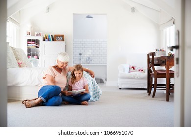 Grandmother and granddaughter reading a book in her bedroom