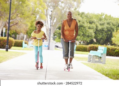 Grandmother And Granddaughter Riding Scooters In Park - Powered by Shutterstock