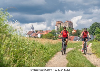 grandmother and granddaughter riding their mountain bikes in front of the awesome skyline of Hiltpoltstein in Frankonian Switzerland, Bavaria, Germany