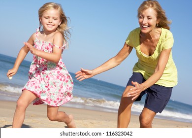 Grandmother And Granddaughter Running Along Beach