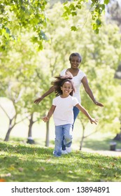 Grandmother And Granddaughter Running In Park And Smiling