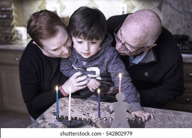 A grandmother and grandfather hold their young grandson as they light the candles for Hanukkah 