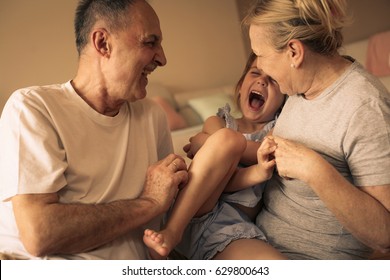 Grandmother and grandfather playing end enjoying with their granddaughter. 
