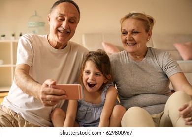 Grandmother and grandfather with their granddaughter making self-picture together.