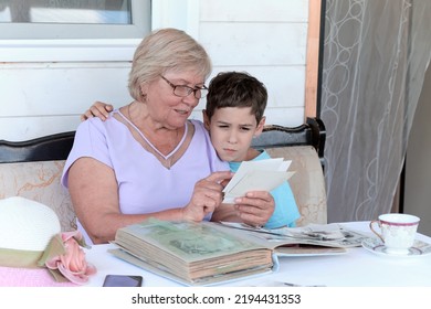 Grandmother and grandson are looking at an photograph album. elderly woman holding album with black and white retro photographs. Happy memories, nostalgia concept. - Shutterstock ID 2194431353