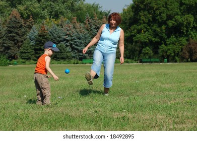 Grandmother and grandson are playing football on the green grass