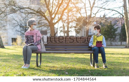 Grandmother and grandson separated by social distancing on park bench