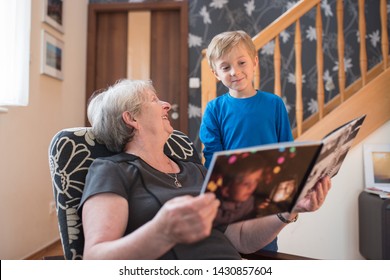 Grandmother and grandson watching photo album with the grandson pictures on the cover