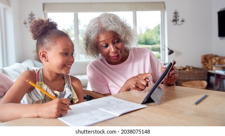 Grandmother Helping Granddaughter With Home Schooling Sitting At Table With Digital Tablet - Powered by Shutterstock