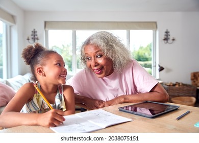 Grandmother Helping Granddaughter With Home Schooling Sitting At Table With Digital Tablet - Powered by Shutterstock