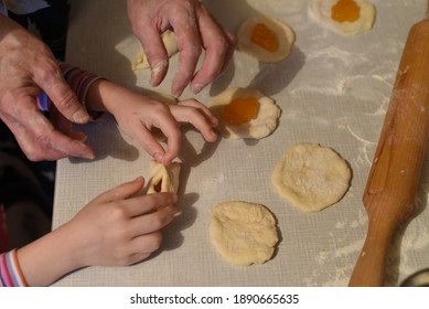 Grandmother helps her granddaughter to make a pie from homemade dough. - Shutterstock ID 1890665635