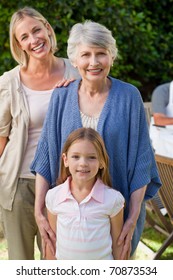 Grandmother With Her Daughter And Grand Daughter Looking At The Camera In The Garden