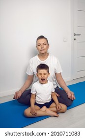 grandmother and her grandson are sitting on a yoga mat in a white apartment at home and meditating in the lotus position