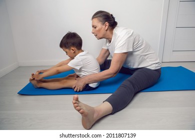 grandmother and her grandson are sitting on a yoga mat in a white apartment at home - Powered by Shutterstock