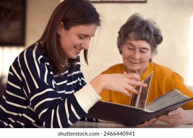 Grandmother and her young granddaughter spent great time together, family members look at photos from the youth of an elderly parent, through the pages of the album and recall funny stories from life. - Powered by Shutterstock