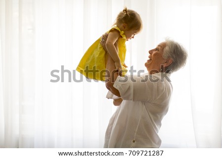 Grandmother holding little granddaughter in the room at home