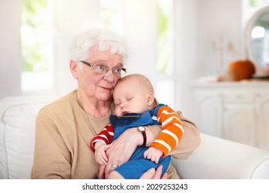 Grandmother Holding Newborn Baby. Family Reunion. Senior Woman With Little Child. Grandma Seeing Grandchild On Thanksgiving Celebration Dinner. Kids Visit Grandparents. Elderly Lady With Infant Kid.