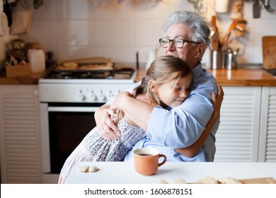 Grandmother hug child girl. Kid and senior woman baking in cozy home kitchen. Happy family enjoying kindness, tenderness, embracing. Lifestyle moment.