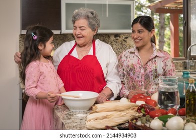 Grandmother and mother talk with their granddaughter and daughter, during the process of preparing the dough to make corn tamales. - Powered by Shutterstock