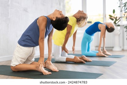 Grandmother, mother and teen son do camel pose Ushtrasana in gym. Family three generations keep fit with exercise. Go in for sports. Healthy lifestyle - Powered by Shutterstock