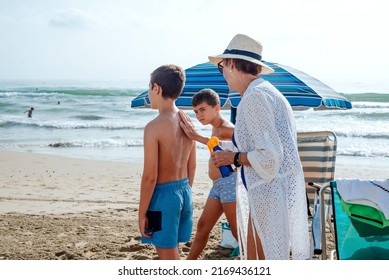 A Grandmother Putting Sunscreen On Her Grandchildren At The Beach. Summer Skin Care Concept