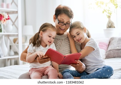 Grandmother reading a book to her granddaughters. Family holiday and togetherness.