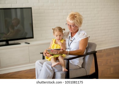 Grandmother reading book to little granddaughter in the room - Shutterstock ID 1051081175