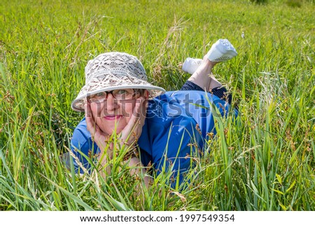 Lachend im Gras liegend, Augen geschlossen.