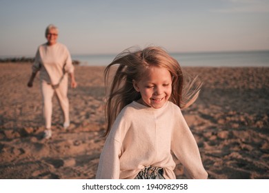 Grandmother runs after her granddaughter on the beach in autumn - Powered by Shutterstock