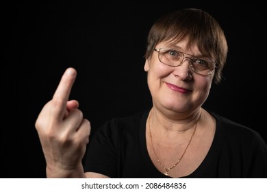 Grandmother Shows Her Middle Finger On A Black Background.