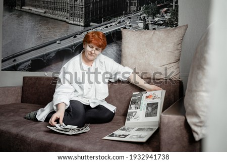 grandmother sits on the couch and looks at photos of her youth, nostalgic for the old days, the city of Kemerovo February 25, 2021